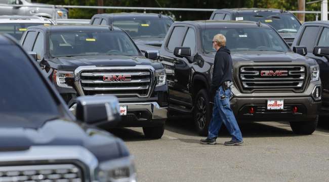 A person wearing a mask looks at vehicles for sale at a car dealership in Woodbridge, N.J., on May 20.