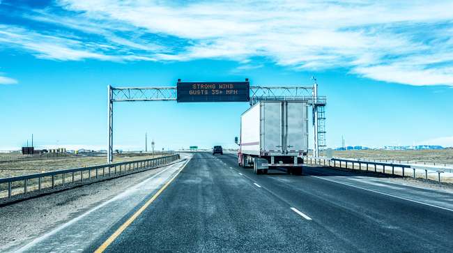 A tractor-trailer passes under an electronic road sign warning of strong wind gusts on Interstate 80 between Cheyenne and Laramie, Wyo.