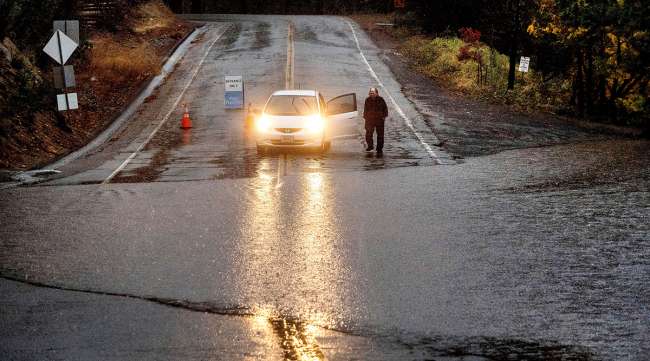 A motorist surveys floodwaters from Lake Madrone crossing Oro Quincy Highway in Butte County, Calif