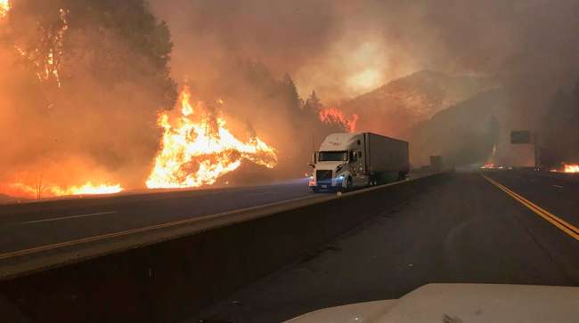 A truck drives next to the Delta Fire burning on I-5