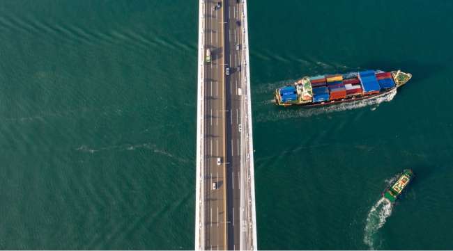 A container ship sails beneath the Busan Harbor Bridge in South Korea on Oct. 13.