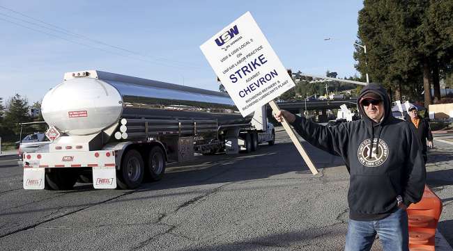 A striking Chevron refinery union worker holds a sign as he pickets outside of the Chevron refinery