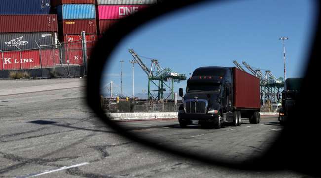 A truck loaded with a shipping container drives through the Port of Oakland in September 2019.