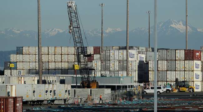 A worker walks near truck trailers and cargo containers in Tacoma, Washington