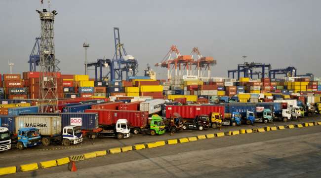 Parked trucks sit in front of shipping containers and cranes at the Manila North Harbour Port container terminal in March 2017.