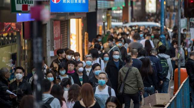 People wearing masks walk on a street in the Kwun Tong district of Hong Kong, China, on Jan. 23.
