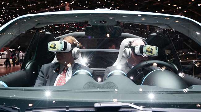Attendees try a virtual reality (VR) experience in Smart Brabus concept vehicle, manufactured by Daimler AG, on the second day of the 86th Geneva International Motor Show in Geneva, Switzerland on Wednesday, March 2, 2016.