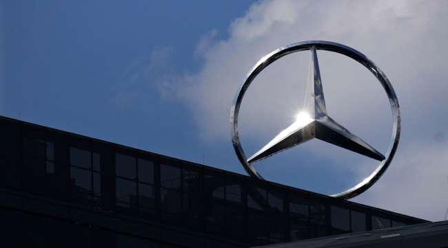 Sunlight reflects in a Mercedes Benz logo on top of an office building in Berlin, Germany.