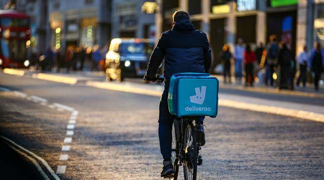 A Deliveroo food carrier cycles along Oxford Street in central London