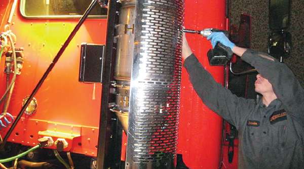 A technician installs a retrofit diesel particulate filter on a truck at the Ironman Renewal facility in San Leandro, Calif.