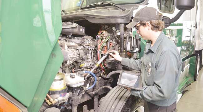 A technician checks diagnostics on a tractor's engine