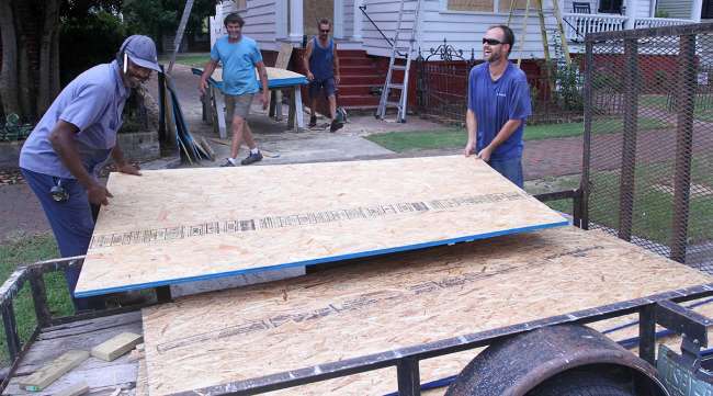 Workers prepare to install plywood panels on a house in New Bern, N.C.