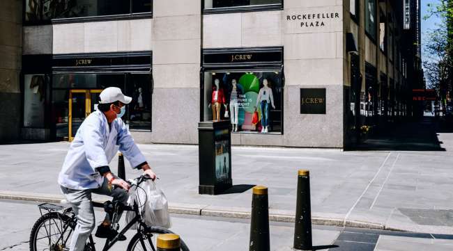 A cyclist wearing a mask passes in front of the J. Crew store in Rockefeller Center in New York on May 5.