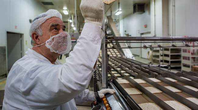 A Mashgiach, a Jew who supervises the kashrut status of a kosher establishment, inspects Passover matzo after it comes out of an oven at the Manischewitz Co. factory in Newark, New Jersey, U.S., on Thursday, Feb. 20, 2014.