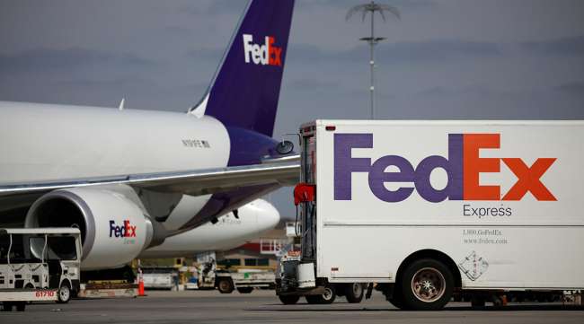 A FedEx delivery truck parked near a cargo jet at the FedEx Express Hub in Memphis.