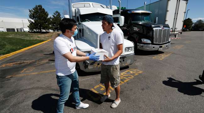 Kavkaz Express employee Bakha Tokkozhin (left) hands a box of food to truck driver Timothy Ellis of Medford, Ore.