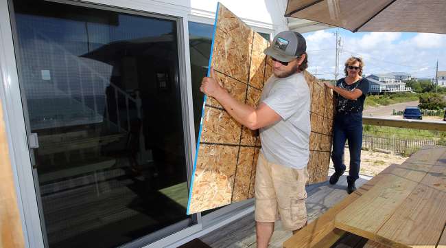 R.I. men move particle board into place to board up the sliding glass doors
