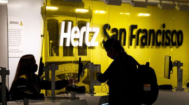 An employee wears a protective mask while assisting a customer at a Hertz counter in San Francisco on May 5.