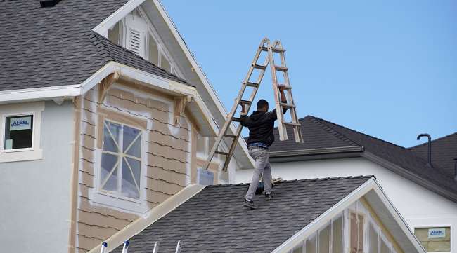 Man working on roof of house