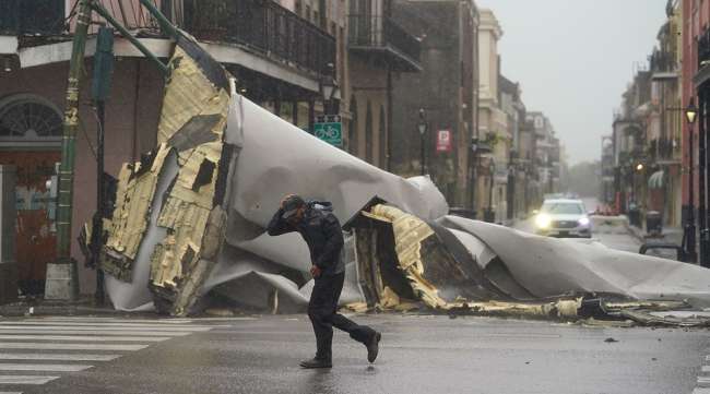 A man in New Orleans' French Quarter passes by a section of a roof blown off by Hurricane Ida