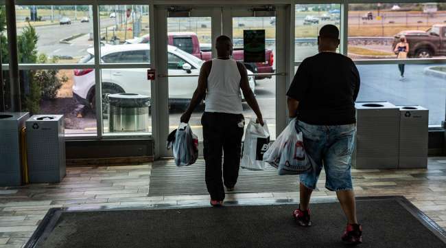 Customers carrying shopping bags exit from a mall in New York.