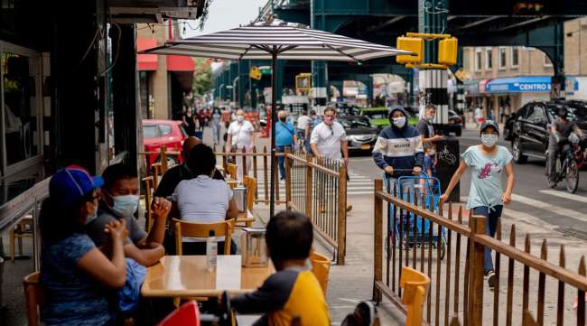 Pedestrians pass in front of restaurant customers in the Queens borough of New York.