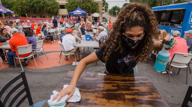 A server cleans a table in an outdoor area at a restaurant in Clemson, S.C.