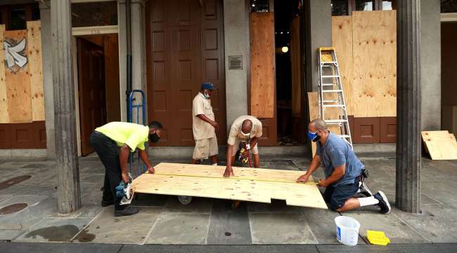 Workers board up windows in New Orleans' French Quarter in anticipation of Marco and Laura.