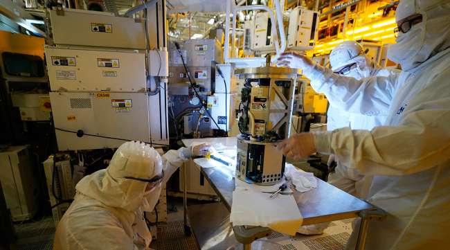 Technicians inspect a piece of equipment at a Micron Technology automotive chip manufacturing plant