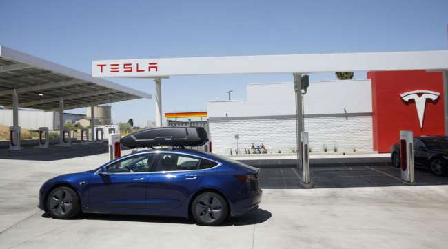 A Tesla Model 3 departs after charging at the Tesla Supercharger station in Kettleman City, Calif., in July 2019.