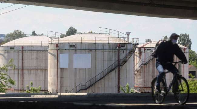 A cyclist wearing a face mask rides past oil storage silos in Belgrade, Serbia, on April 28.
