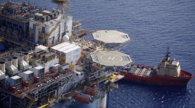 A platform supply vessel sits anchored next to a deepwater oil platform in the Gulf of Mexico.