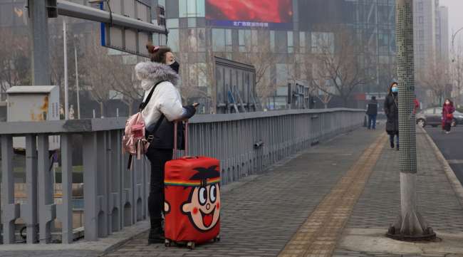 A traveler wearing a mask stands on a bridge in Beijing China, on Feb. 13