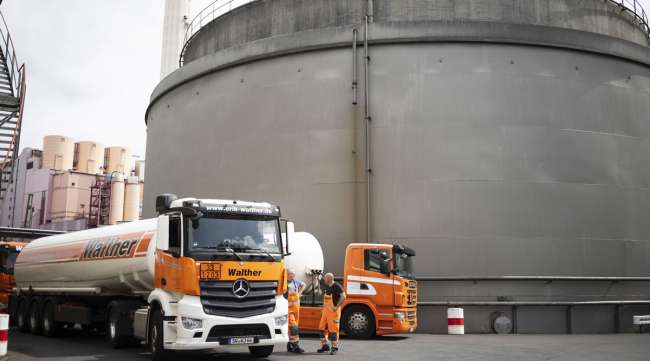Oil tanker trucks sit parked beside storage silos in Germany in June 2019.