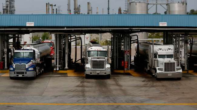 Trucks transporting oil exit a Valero facility