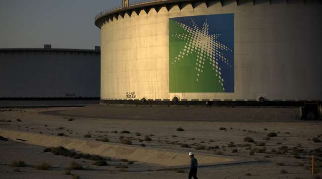 Employee walks past crude oil storage tanks  in Saudi Arabia