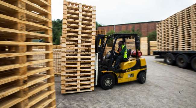 A forklift truck moves a stack of heat-treated wooden pallets.