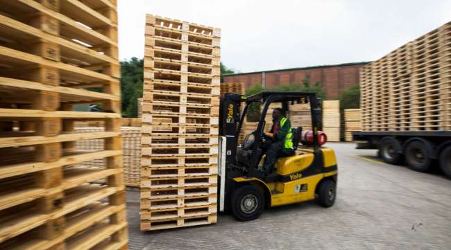 An employee uses a forklift truck to move a stack of heat-treated wooden pallets. (Chris Ratcliffe/Bloomberg News)