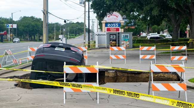 Ocala, Fla, - June 11, 2017: A sinkhole opens in a parking area and swallows a car that teeters on the edge.