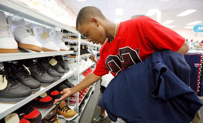 Alex Atkins, 13, looks for a new pair of shoes to go with his new school uniforms at a clothing store