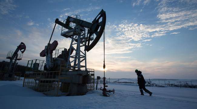 An oil worker inspects a pumping jack in a Russian village