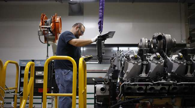 A worker assembles components on a diesel engine