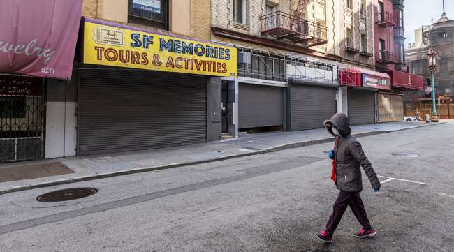 A pedestrian passes closed stores in San Francisco.