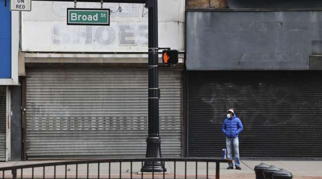 A pedestrian stands in front of closed stores in Newark, N.J., on Nov. 25. (Angus Mordant/Bloomberg News)