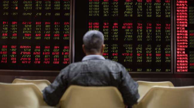 An investor looks at stock price movements on screens at a securities company in Beijing.