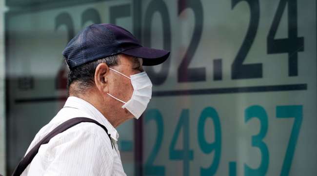 A masked man looks at an electronic stock board in Tokyo on July 27.