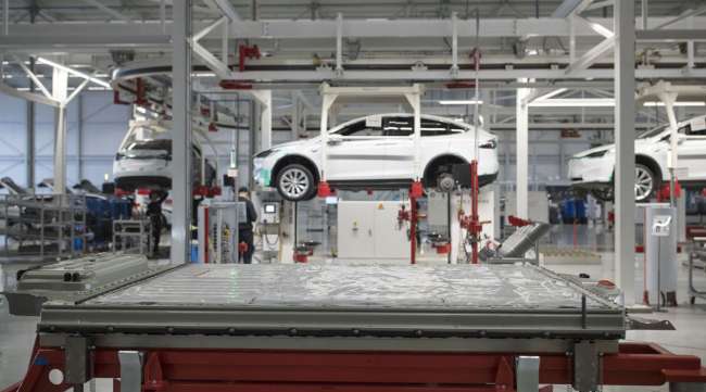A battery pack sits on a trolley before a Tesla Model X at a factory in Netherlands.