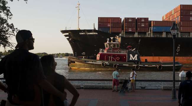 People watch as a cargo ship and tug boat travel into the Port of Savannah. (Ty Wright/Bloomberg News)