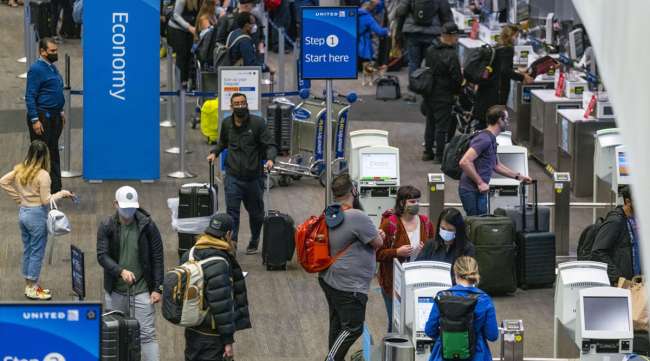 Travelers wearing protective masks check in at San Francisco International Airport on Nov. 24.