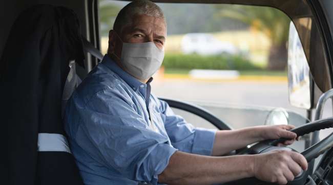 Trucker in cab wearing mask